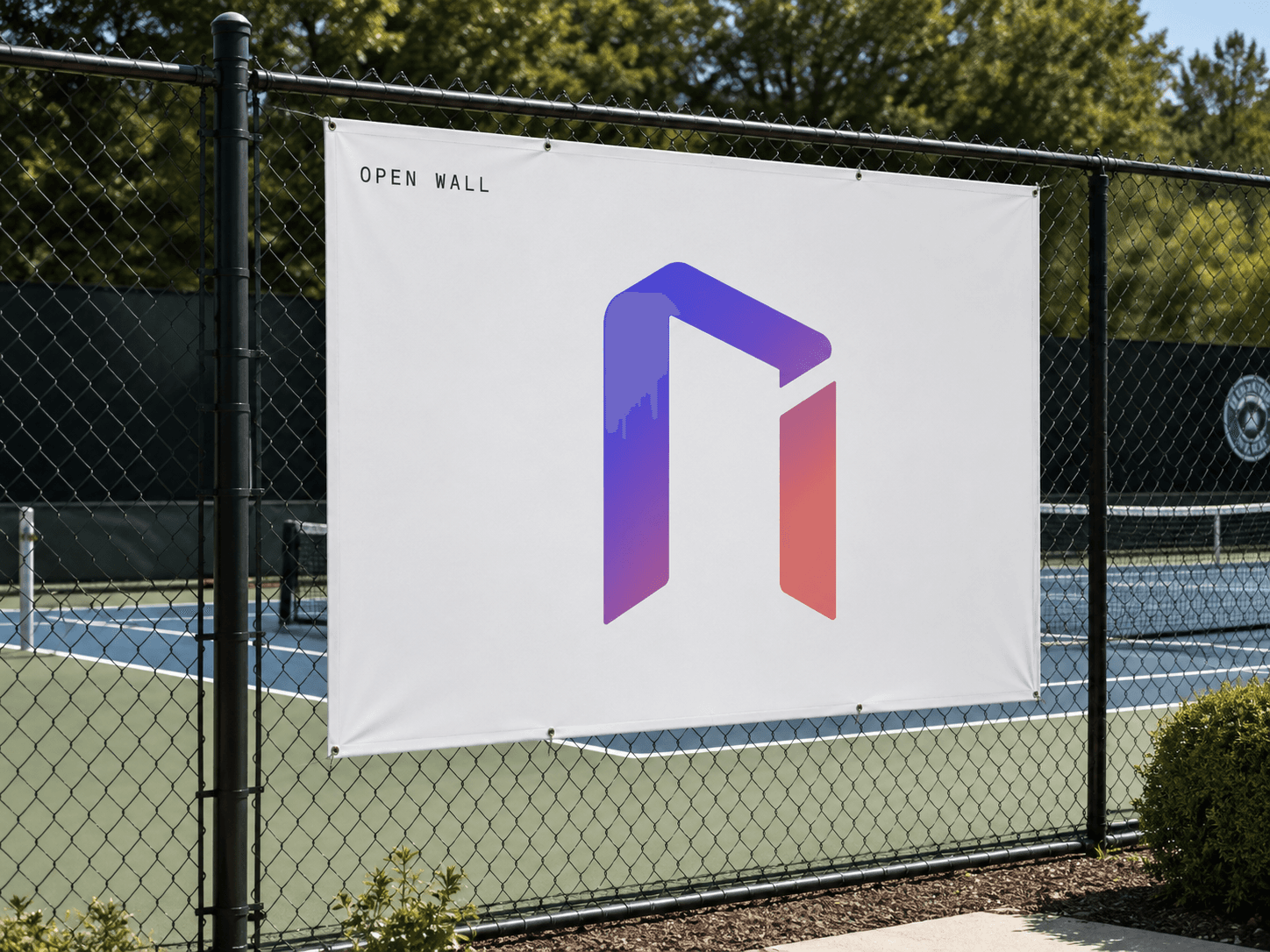 An OpenWall banner on a fence beside a community tennis court